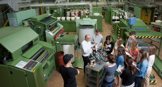 Gruppe von Studierenden wird in der Betriebshalle im Fachbereich Textil und Design unterrichtet.